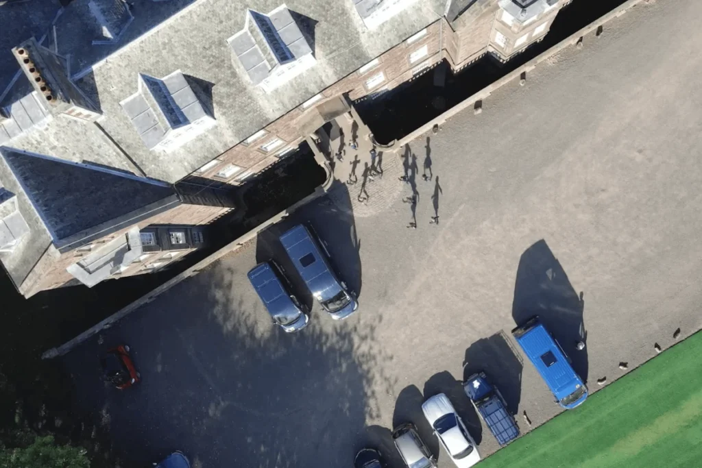 Aerial view Bellhaven Hill School with several parked vehicles and a group of people in the yard