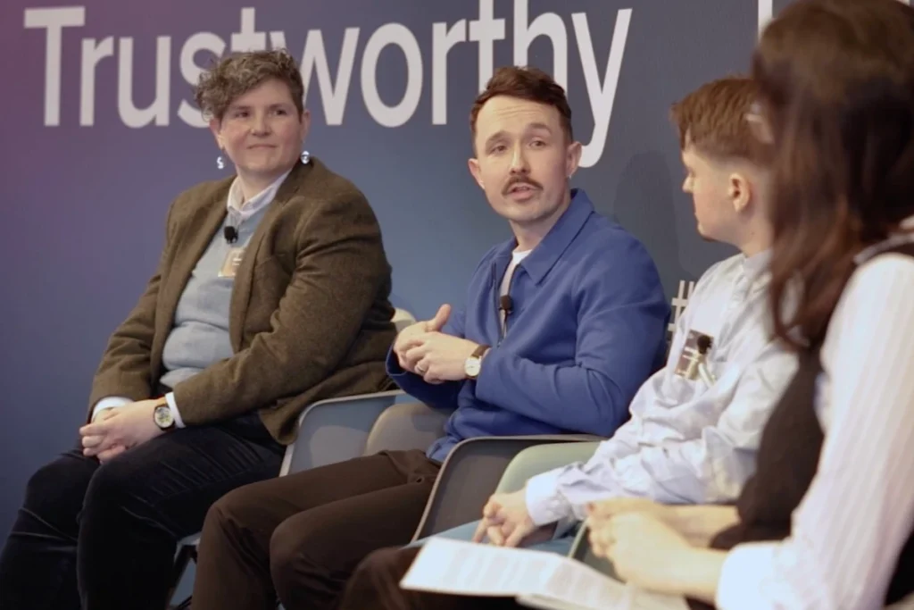Panel discussion on trustworthiness featuring four speakers sharing insights and experiences in a professional setting.