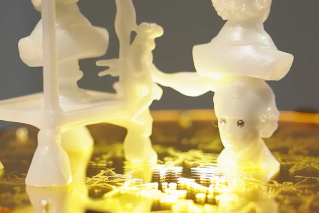 Off-white, abstract figures on a lighted, gold-coloured surface